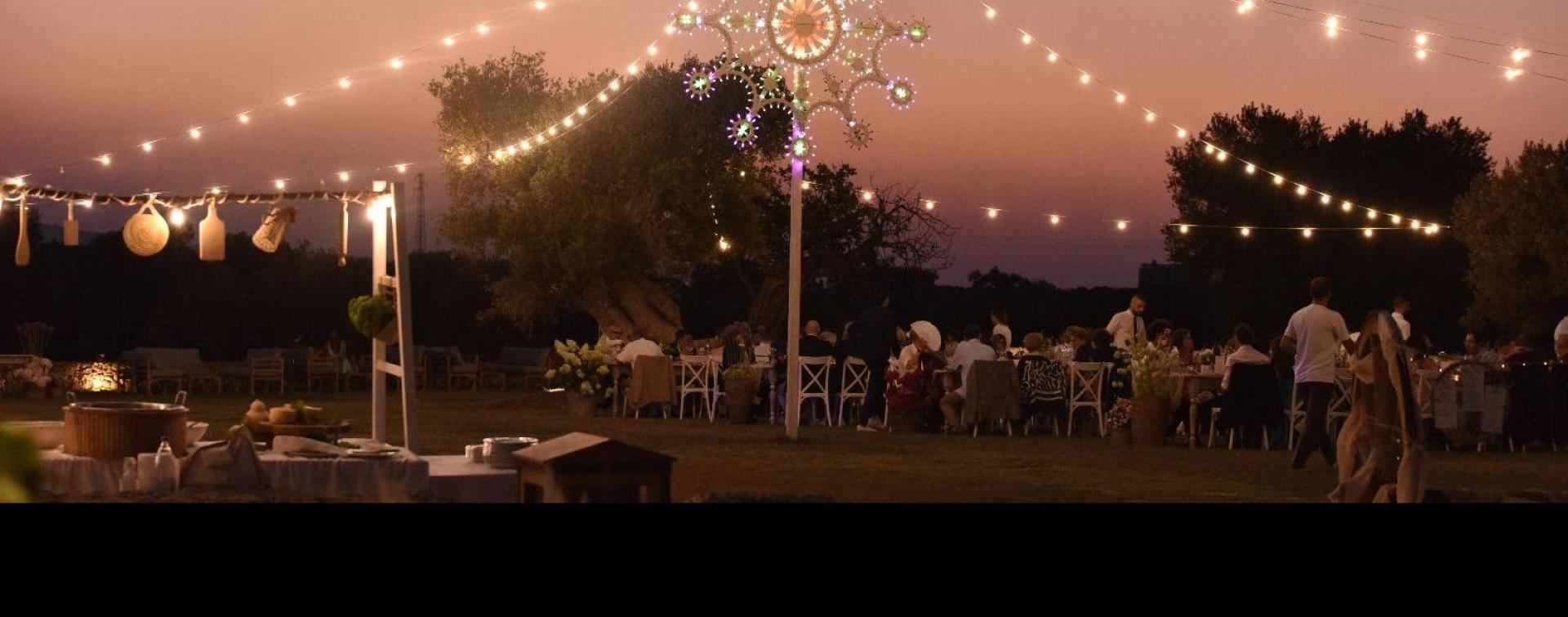 Outdoor dinner with decorative lights at sunset.